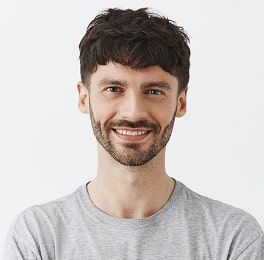 Smiling man with short hair and beard in gray shirt
